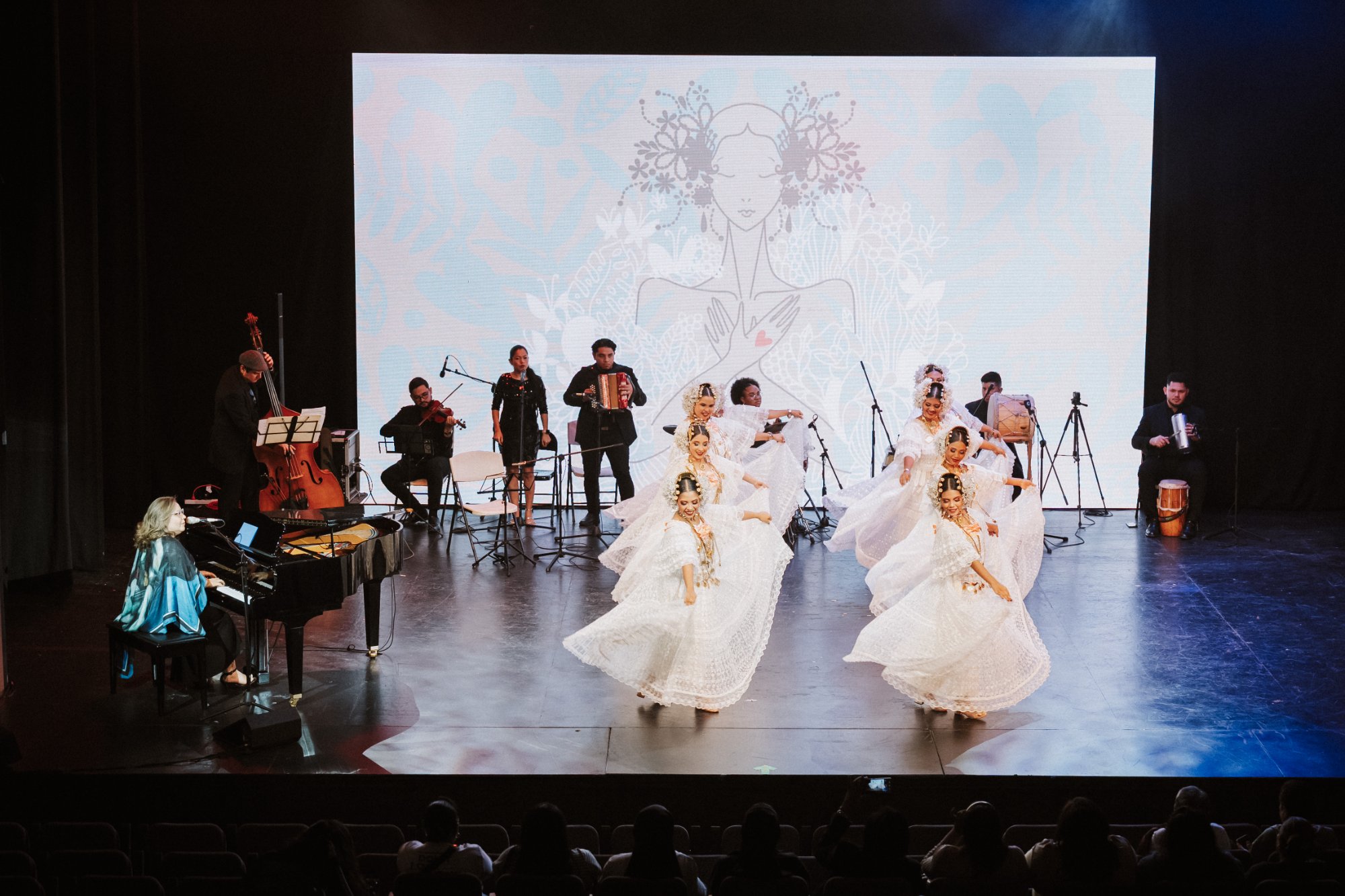 Patricia al piano con bailarinas de pollera y orquesta